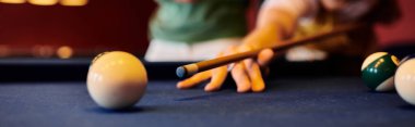 Bilardo sopasıyla nişan alıp beyaz bilardo topuna odaklanan bir adam..