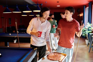 Arkadaşlar sıradan bir ortamda bilardo masasında durup arkadaşlarıyla pizza ve içkinin keyfini çıkarırlar..