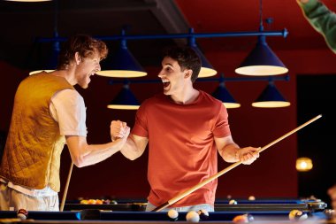 Friends celebrate a win at a pool table, smiling and high-fiving. clipart