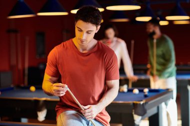 Bir adam dostça bir bilardo maçı sırasında atışına konsantre olur..
