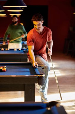 Arkadaşlar iyi aydınlatılmış bir odada bilardo oynarlar, rahat ve şık kıyafetlerini sergilerler..