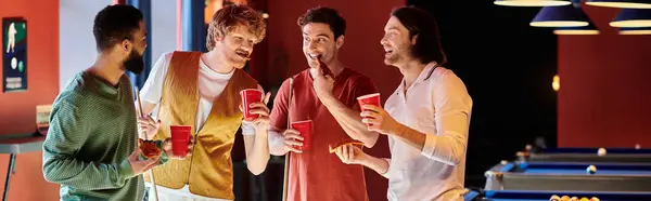 stock image Friends chat and laugh while enjoying a game of billiards and drinks in a dimly lit setting.