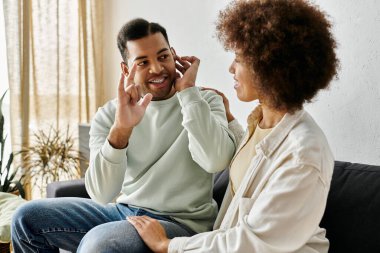 Afro-Amerikalı bir çift evdeki koltukta oturup işaret dili kullanarak iletişim kuruyor..