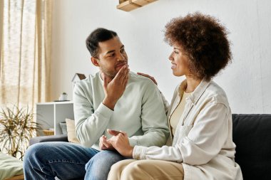 Afro-Amerikalı bir çift evdeki koltukta oturup işaret dili kullanarak iletişim kuruyor..