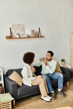 Afro-Amerikalı bir çift kanepede oturur ve iletişim kurmak için işaret dili kullanır..