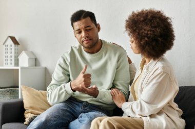 Afro-Amerikalı bir çift evdeki kanepede otururken işaret diliyle iletişim kuruyor..