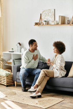 Afro-Amerikalı bir çift kanepede oturur ve iletişim kurmak için işaret dili kullanır..