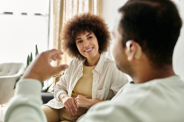 An African American couple signs to each other while sitting at home. clipart