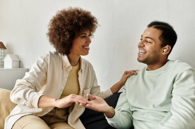 Afro-Amerikalı bir çift evdeki kanepede otururken işaret diliyle iletişim kuruyor..