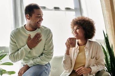 An African American couple communicates through sign language in a cozy living room, creating a heartwarming scene of intimacy and connection. clipart