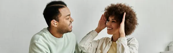 stock image An African American couple uses sign language to communicate and smile at each other in their home.