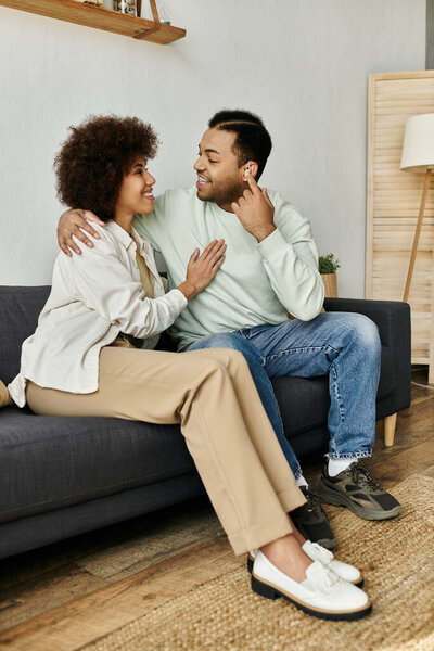 Привлекательная афроамериканская пара сидит на диване в своем доме и общается с языком жестов.