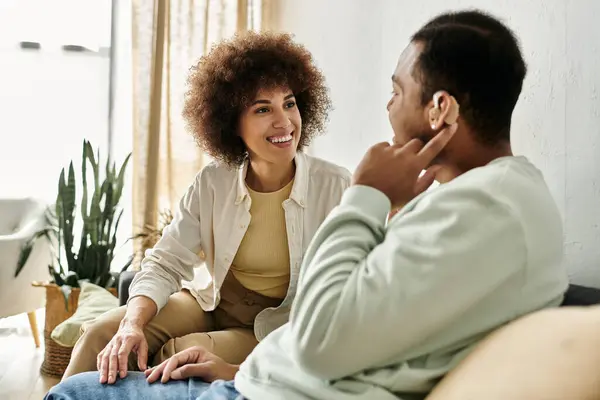 stock image An African American couple sits on a couch, conversing in sign language, creating a heartwarming and intimate moment.