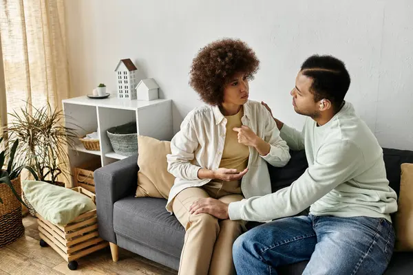 stock image A couple sits on a couch at home, using sign language to communicate.