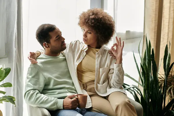 stock image An African American couple sits together, using sign language to communicate at home.