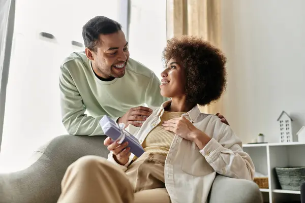 stock image Loving African American woman near her husband with hearing aid, gift in hands.