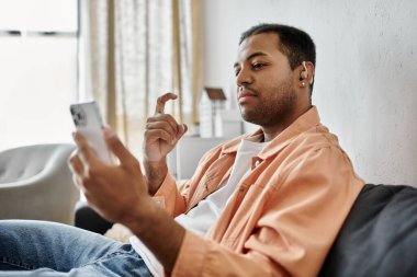Genç bir Afrikalı Amerikalı adam akıllı telefonunu kullanırken elleriyle imzalıyor..
