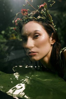 A woman with a flower crown poses near a swamp, looking directly at the camera. clipart