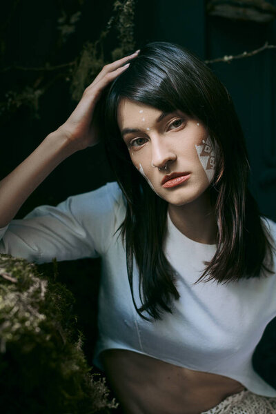A woman with striking makeup poses near a swamp.