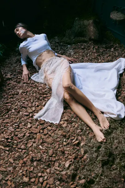 stock image A woman in ethereal clothing poses on a bed of wood chips.