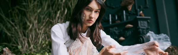 A woman poses in a swamp surrounded by plastic garbage.