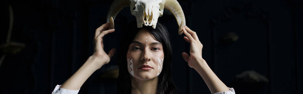 A woman with painted face and a skull crown stares intently at the camera.