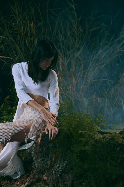 Woman in white dress by swamp.