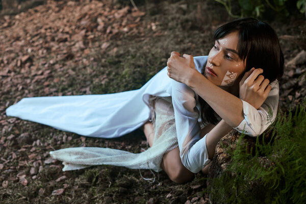 Женщина позирует в темной белой одежде возле болота.