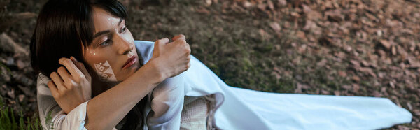 A woman in elegant attire poses near a swamp.