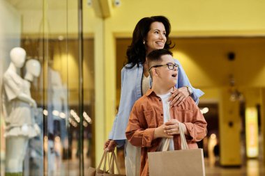 Down sendromlu bir anne ve oğlu alışveriş merkezinde birlikte yürüyüp birbirlerine eşlik ediyorlar..