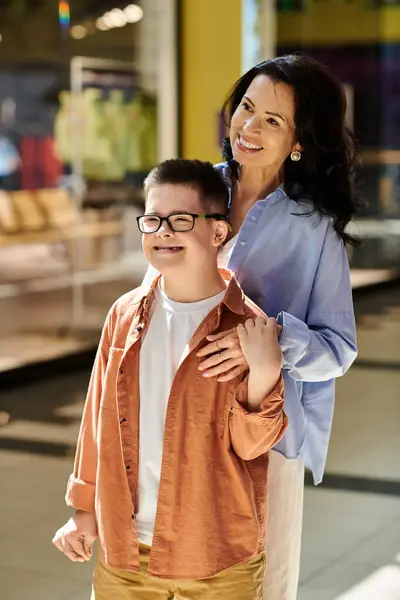 stock image A mother and her son with Down syndrome walk hand-in-hand through a shopping mall, enjoying quality time together.