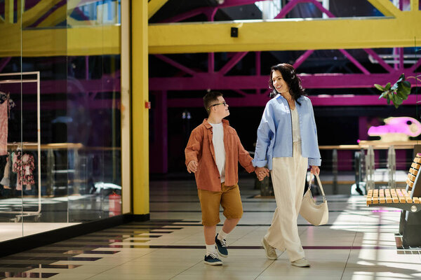A mother and her son with Down syndrome walk hand-in-hand through a shopping mall, smiling and enjoying their time together.