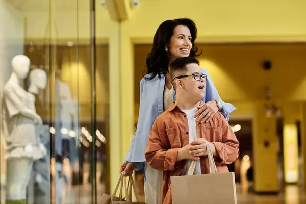 stock image A mother and her son with Down syndrome are walking through a shopping mall together, enjoying each others company.