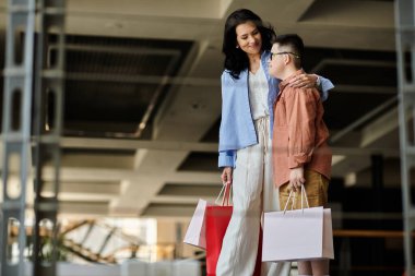 A mother and her son with Down syndrome walk through a shopping mall, enjoying their time together. clipart