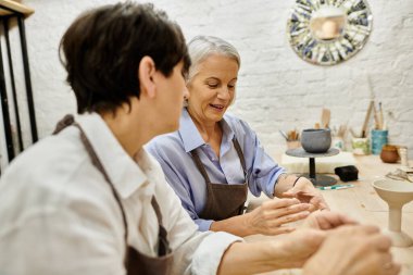 İki kadın, olgun bir lezbiyen çift, bir sanat stüdyosunda çömlek üzerinde birlikte çalışıyorlar..