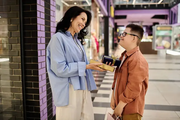 stock image A mother and her son with Down syndrome exchange gifts while walking through a shopping mall.