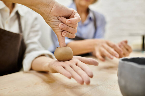 A close-up of a womans hand shaping clay, showcasing the intimate artistry of pottery.