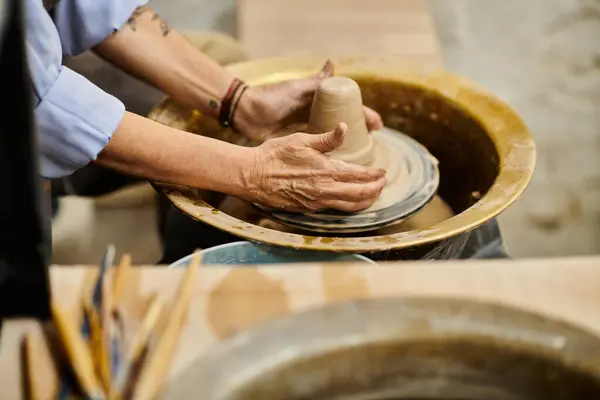 stock image A close-up of a mature woman working on a pottery wheel in an art studio.