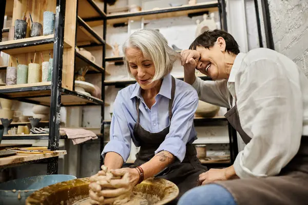 stock image A mature lesbian couple laughs and works on pottery in a cozy studio.