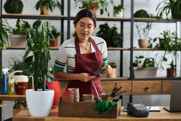 stock image An Asian woman in an apron stands behind the counter of her plant shop