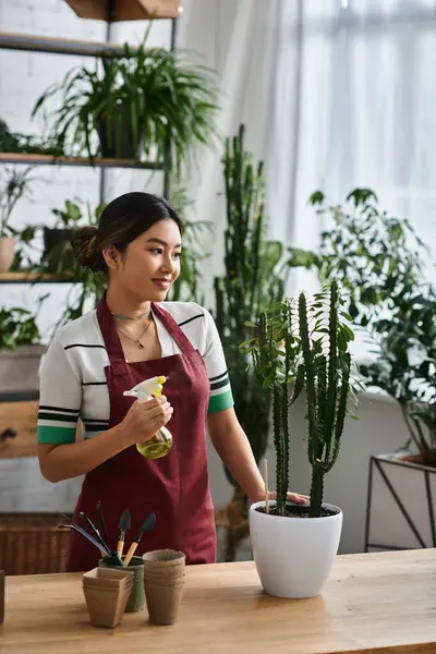 Çiçek dükkanı sahibi önlüklü genç bir Asyalı kadın bitkileri suluyor..