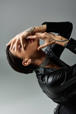 Siyah derili genç bir kadın gri bir arkaplanda poz veriyor..