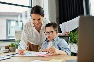 Down sendromlu bir anne ve oğlu modern bir ofiste birlikte çalışıyorlar. Oğlu boya yaparken annesi evrak işleriyle uğraşıyor..