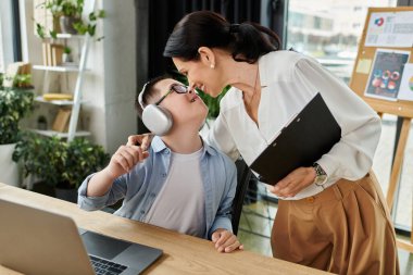 Down sendromlu bir anne ve oğlu modern ofis ortamında yan yana çalışıyorlar..