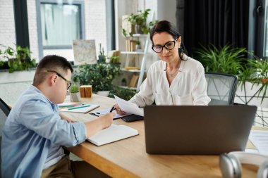 Down sendromlu bir anne ve oğlu, işyerlerindeki çeşitliliği vurgulayarak kapsamlı bir ofiste çalışıyorlar..