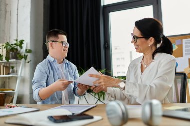 A mother and her son, who has Down syndrome, work side-by-side in an office setting, sharing a lighthearted moment. clipart