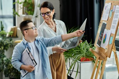 A mother and her son with Down syndrome work together on a project in an office setting. clipart