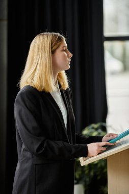 Teenage girl, dressed in a black suit, gives a speech at a UN Model conference. clipart