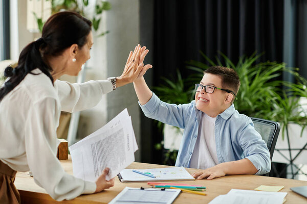 A mother and her son with Down syndrome celebrate a successful work session together in their home office.