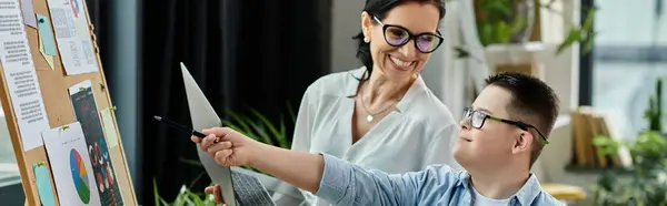 stock image A mom and her son with Down syndrome work in a home office, promoting inclusion and diversity in family life.